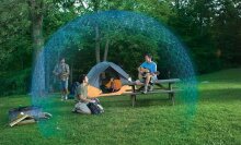 People walking or sitting around their camp setup in the woods with a blue, forcefield-like bubble around them