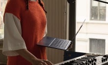 person holding 2022 m2 macbook air in front of a piano