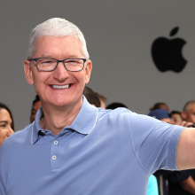 Tim Cook in front of an Apple logo flashing a peace sign