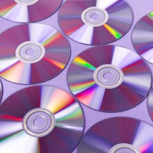 Many DVDs lined up in a pattern over a purplish background